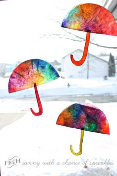 three umbrellas made out of paper sitting on the window sill in the snow