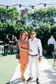 a man and woman standing next to each other in front of an outdoor dining area