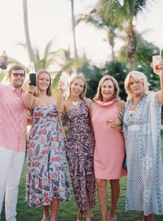 four women and one man are posing for the camera with drinks in their hands,