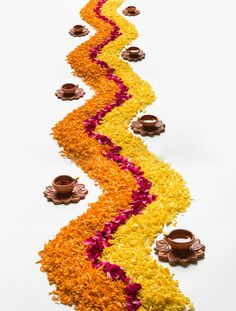 a long row of flowers and candles on the ground in front of a white background