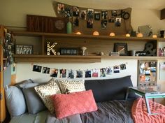 a bed with lots of pillows and pictures on the wall above it, along with bookshelves