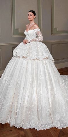 a woman in a white wedding dress standing on a wooden floor with her hands on her hips