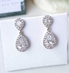 a pair of diamond earrings sitting on top of a card