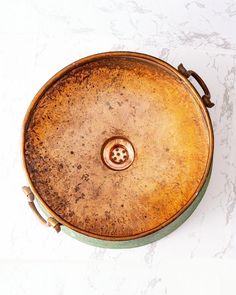 an old round metal container sitting on top of a white countertop next to a wall