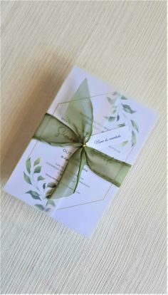 a wedding card with a green ribbon tied around the front and back of it, sitting on top of a table