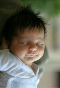 a close up of a baby laying on top of a bed with its eyes closed