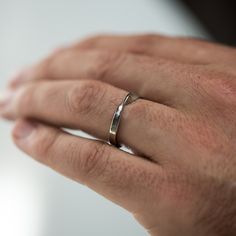 a man's hand with a wedding ring on his left hand, wearing a silver band