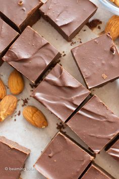 almonds and chocolate on a table next to some pieces of chocolate that have been cut into squares