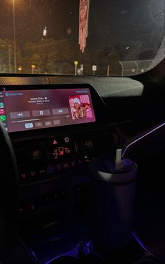 the dashboard of a car with an electronic device on it's display screen and lights in the background