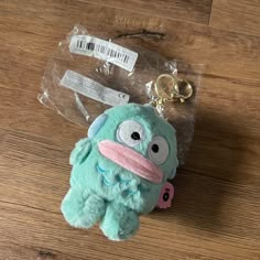 a stuffed animal keychain sitting on top of a wooden floor next to a plastic bag