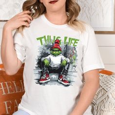 Thug Life Grinchmas Shirt | Funny Christmas Tee | Grinch Lovers Christmas Gift Idea Get into the holiday spirit with a twist of humor with this "Thug Life Grinchmas" shirt! Perfect for fans of the classic Grinch, this funny Christmas tee is great for family gatherings, movie nights, or as a unique Christmas gift idea for Grinch lovers. Spread festive cheer with a dash of attitude and give everyone a laugh this holiday season! Funny Christmas Shirt, Grinch Christmas Gift, Thug Life Grinch 🌟 How to Order:  1️⃣ Check all photos carefully. 2️⃣ Select your t-shirt size and color. Note: Slight color variations may occur due to different brands. For exact color matching, choose the same style (e.g., Unisex, V-necks, Toddler). 3️⃣ Add to cart, and feel free to add more items. 4️⃣ Proceed to check Christmas Cotton T-shirt For Streetwear, Christmas Streetwear Cotton T-shirt, Cotton Christmas T-shirt For Streetwear, Family Christmas Movies, Funny Christmas Tshirts, Christmas Tshirt, Funny Christmas Shirts, Christmas Movie, Movie Nights