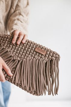 a woman holding a brown knitted purse with tassels on the bottom and sides