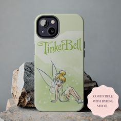 a tinker bell phone case sitting on top of a rock