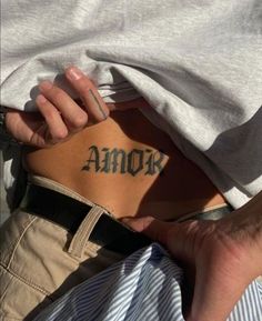 a person with a tattoo on their back holding onto another persons arm and the word amok written in cursive ink