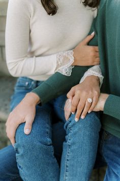 an engaged couple sitting on a bench holding hands