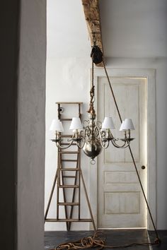 a chandelier hanging from the ceiling in front of a door with ladders