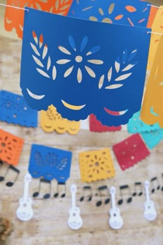 colorful paper cutouts hanging from strings with music notes and guitar string attached to them