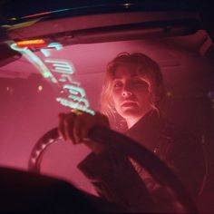 a woman sitting in the driver's seat of a car with neon writing on it