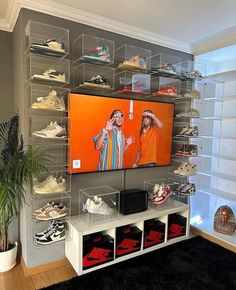 a large television mounted to the side of a wall with shoes on display in front of it