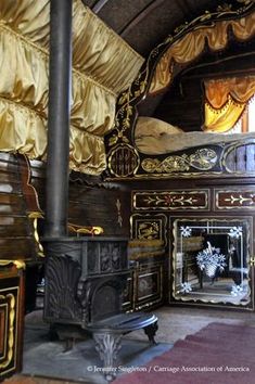 an old fashioned bedroom with gold drapes on the ceiling and wooden furniture in it