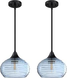 two black and clear glass pendant lights hanging from a ceiling fixture with one light on each side