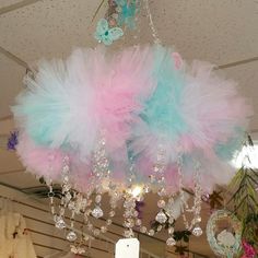 a chandelier with pink and blue feathers hanging from it's centerpiece