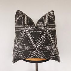 a black and white pillow sitting on top of a wooden stand