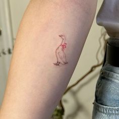 a woman's arm with a small tattoo of a bird on it and a bow around its neck