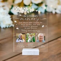 an acrylic memorial plaque on a wooden table with flowers and greenery in the background