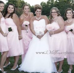 a group of women standing next to each other wearing pink dresses and holding bouquets