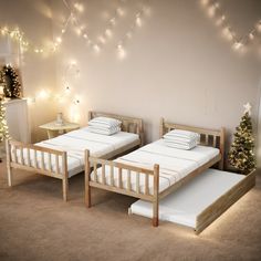 two twin beds in a bedroom with christmas lights on the wall and tree behind them