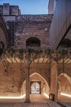 the inside of an old building with stone arches and arched doorways, lit up at night