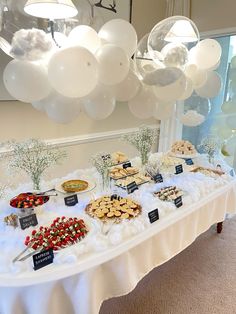 a table topped with lots of desserts and balloons hanging from the ceiling above it