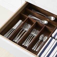 an open drawer with silverware and striped napkins