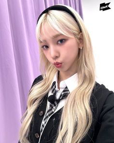 a woman with long blonde hair wearing a black and white shirt, bow tie and headband