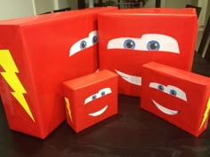 four red boxes with faces and lightning bolt painted on them, sitting on a table