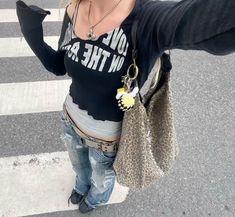 a woman is taking a selfie with her cell phone in the street while wearing jeans and a t - shirt that says love on the back