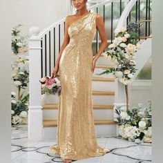 a woman in a gold dress posing for the camera with flowers and stairs behind her