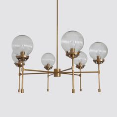 a brass chandelier with five glass globes hanging from the bottom and four lights on each side