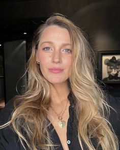 a woman with blonde hair and blue eyes posing for a photo in a black shirt