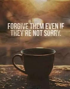 a coffee cup sitting on top of a wooden table next to a stone wall with the words, for give them even if they're not sorry