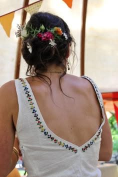 a woman with flowers in her hair wearing a white top and colorful garland on her head