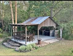 an outdoor kitchen and dining area in the middle of a wooded area with steps leading up to it