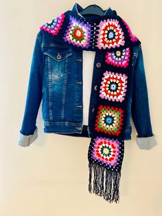 a blue jean jacket with crochet on it and a scarf hanging from the back