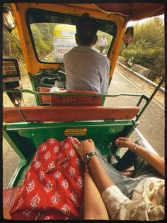 two people sitting in the back of a green truck