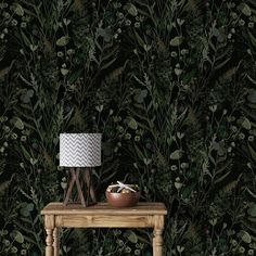 a wooden table with a lamp on it in front of a green wallpaper