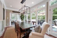 a large dining room table and chairs in front of windows