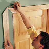 a man in yellow shirt holding up a wooden door frame to the wall with his hands