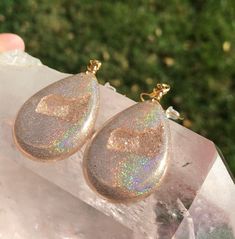 These holographic Teardrop geode earrings made from resin shift from clear gold to a beautiful sparkly rainbow. They are lightweight and won't bother your ears. Please be aware that resin is heat resistant up to 135 degrees. Wearing these earrings in extremely hot temperatures will cause them to be pliable. If this happens, simply place in a cooler location. I am not responsible for any damaged earrings due to extreme heat. Made by Katie Glover Resin Art by Katie 2020 Contact me on my Instagram Sparkling Dangle Teardrop Earrings Gift, Sparkling Teardrop Dangle Earrings As Gift, Teardrop Sparkling Jewelry For Gift, Hypoallergenic Resin Jewelry For Parties, Iridescent Sparkling Jewelry As Gift, Iridescent Sparkling Jewelry Gift, Sparkling Iridescent Jewelry As Gift, Unique Gold Teardrop Earrings Gift, Unique Gold Crystal Earrings As Gift