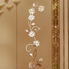 the wall is decorated with white flowers and gold trimmings, along with an intricately designed mirror